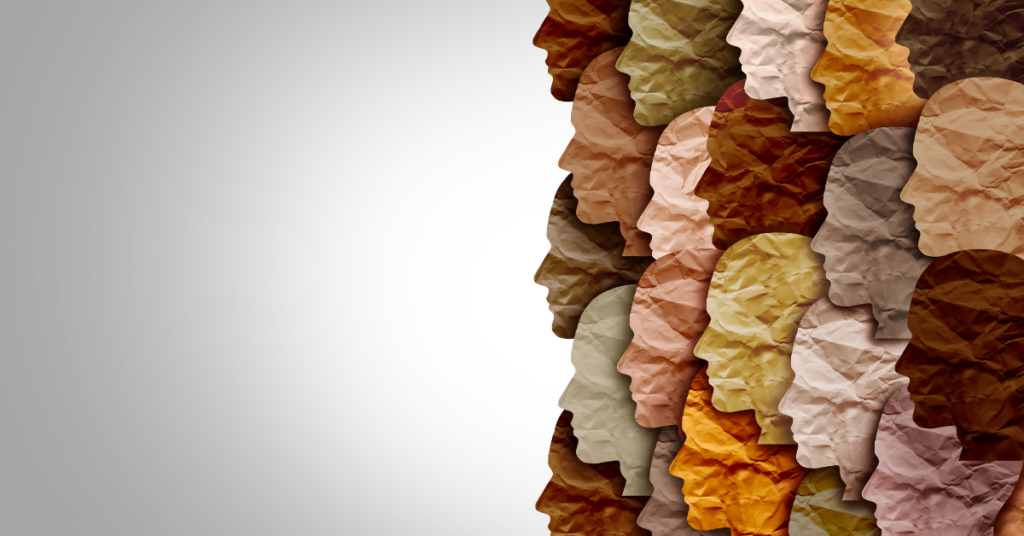 Graphic artwork of various silhouetted human face shapes in profile and made of various colors of crinkled paper, implying individuals of various cultures, all overlapping with each other and grouped on the right side of the image and facing to the left, which contains a blank, light colored space that contains a gradual darkness gradient