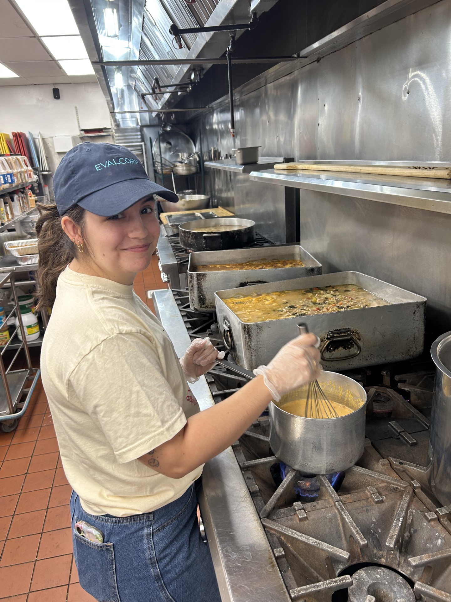 Photo of team member Reighan in front of stovetop making soup in for her volunteer shift