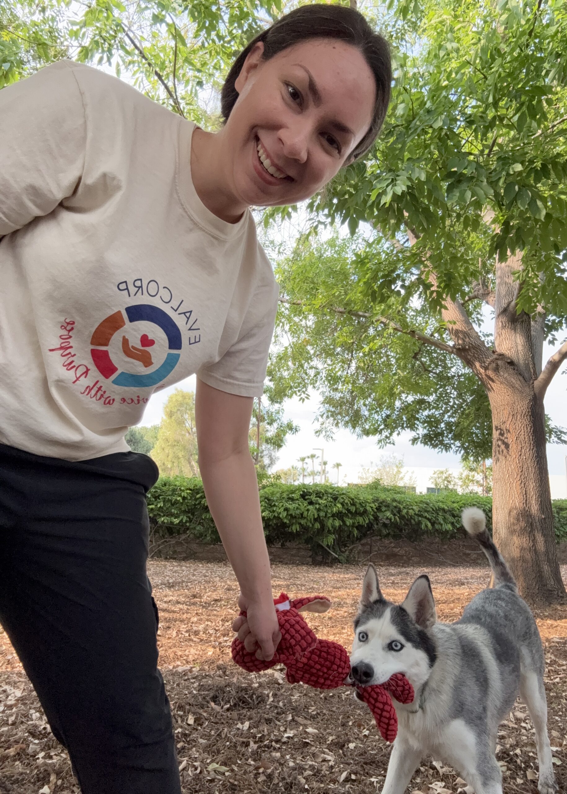 Photo of team member Taylor volunteering at an animal shelter playing with a gray and white dog