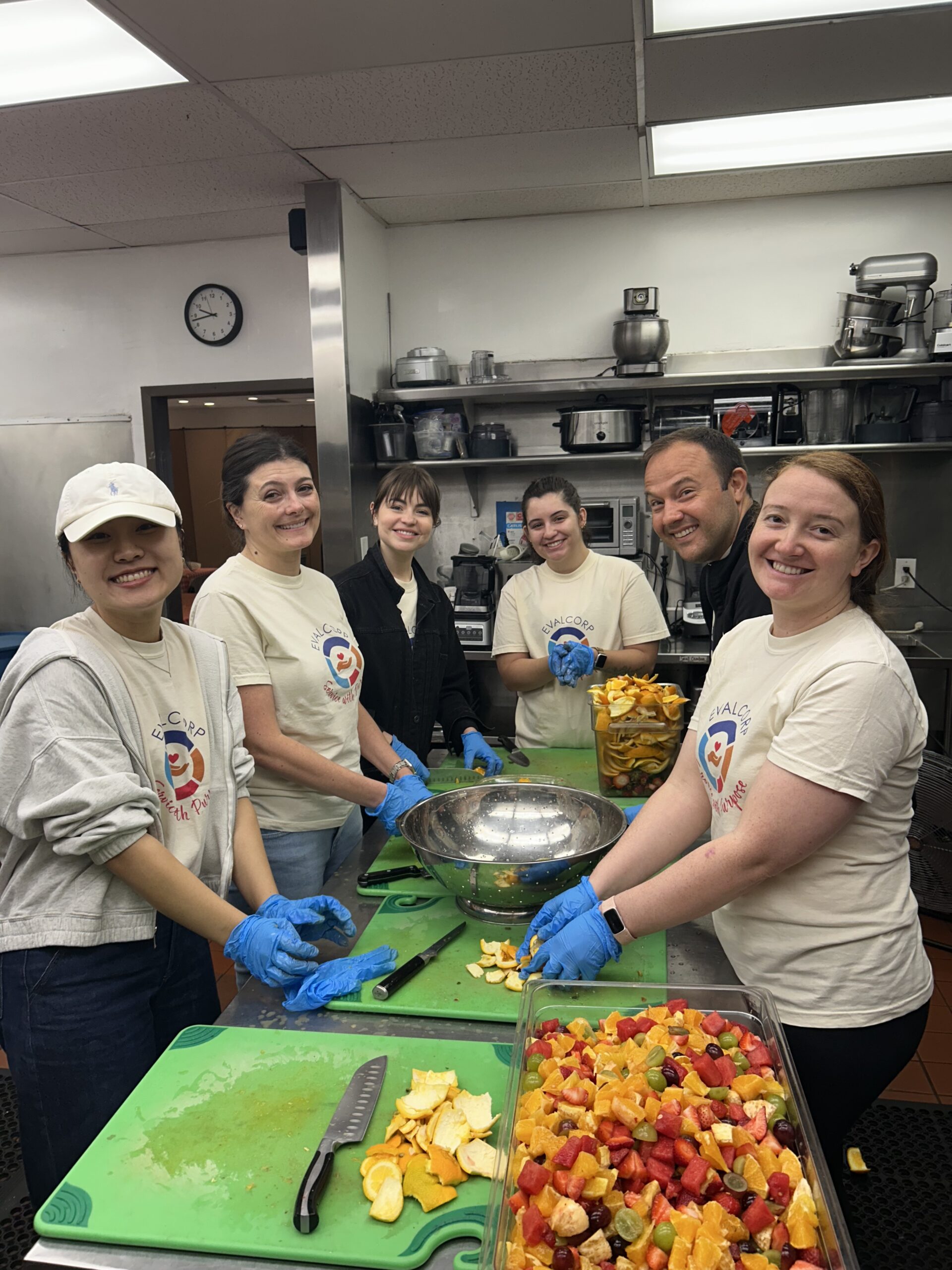 Photo of EVALCORP team members making fruit salad in community kitchen